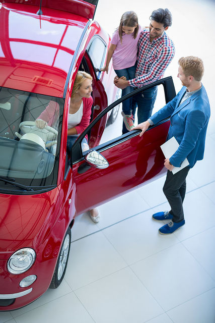 woman sitting in car looking at family